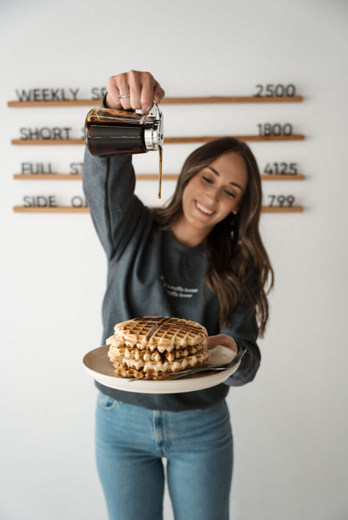 kelly dripping syrup on stack of waffles