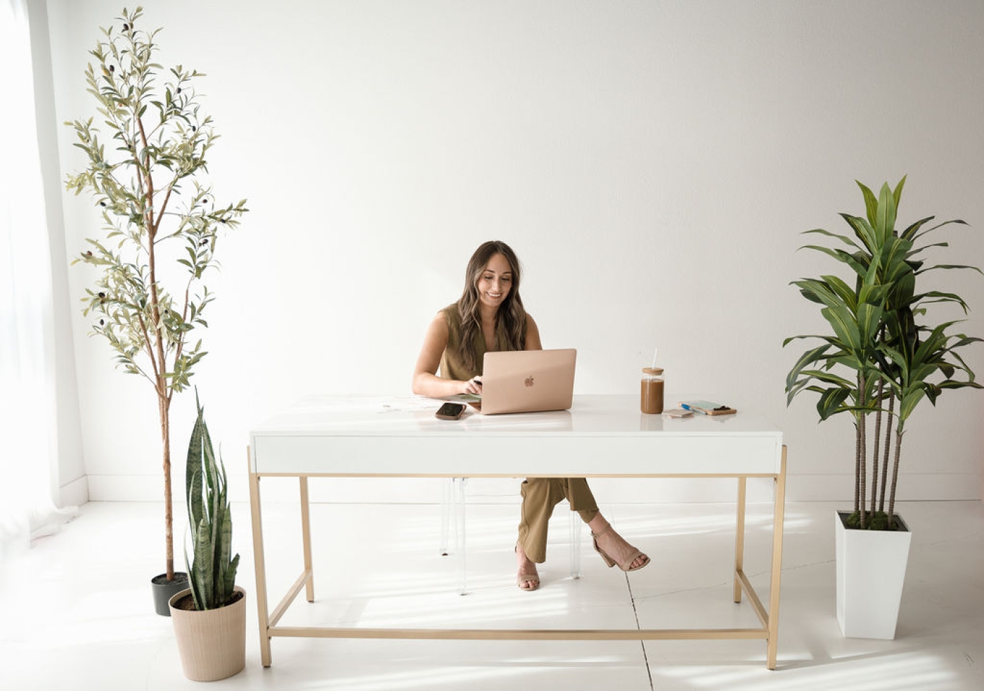 A website designer for small business owners sitting at a white and gold desk in a studio