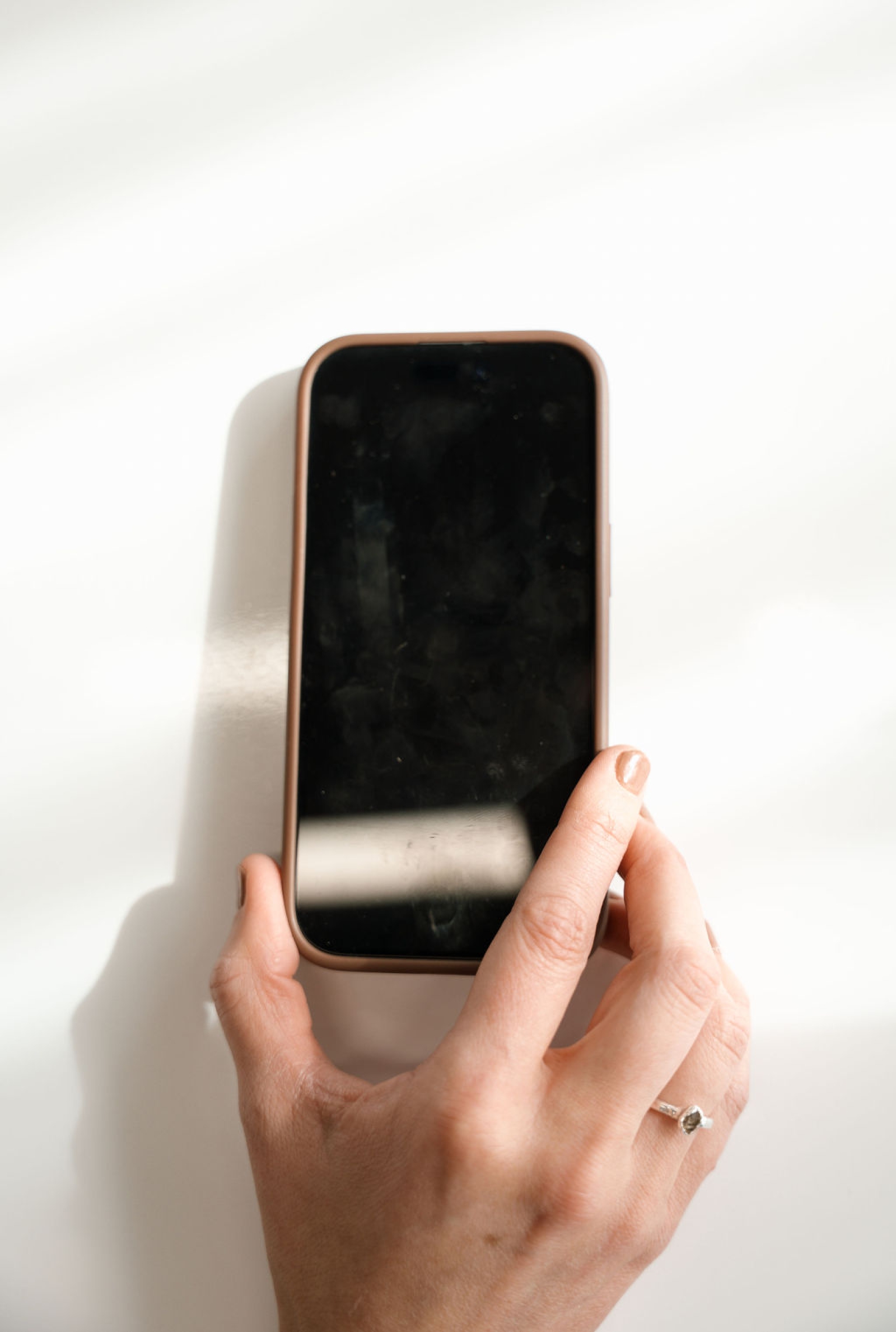 A woman holds an iPhone on a blank background