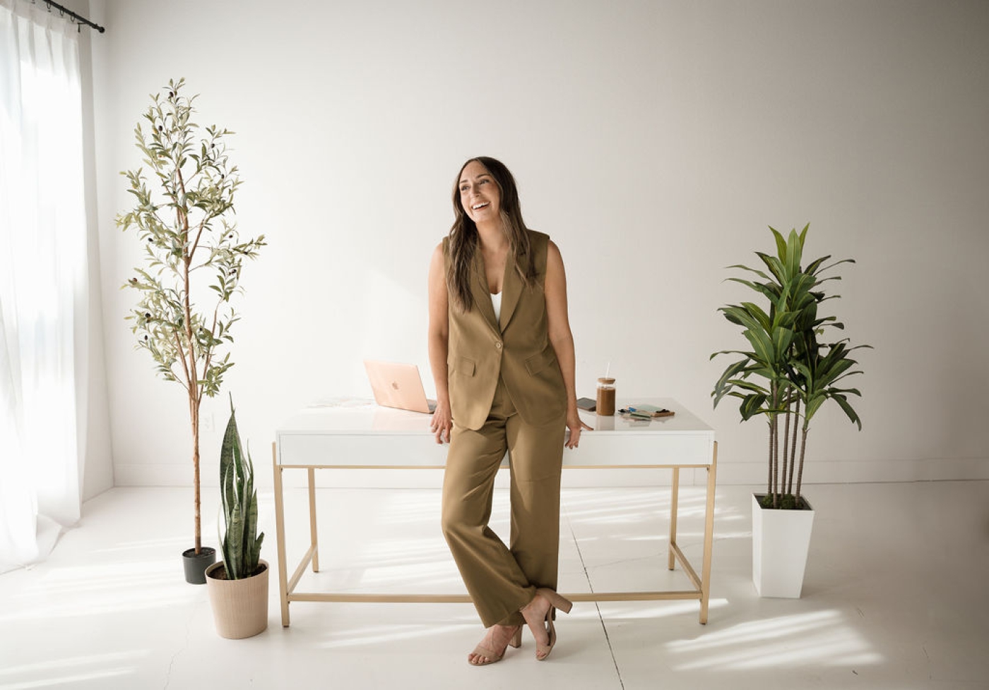 A web designer in a sleeveless suit leans against a desk